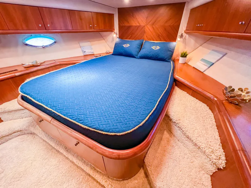 Slide: The Image of Luxurious 2005 Sunseeker Predator 68 yacht bedroom with blue bedding and wooden accents. - 17