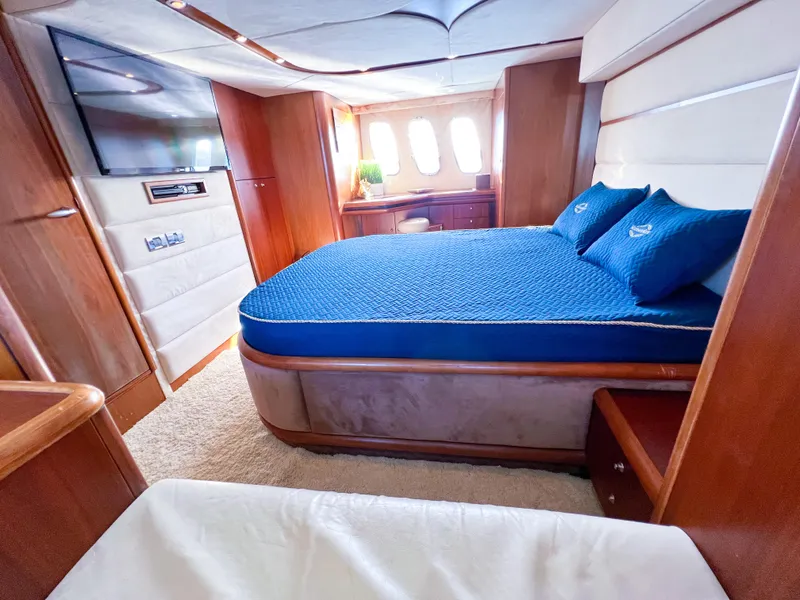 Slide: The Image of Luxurious 2005 Sunseeker Predator 68 yacht bedroom with blue bedding and elegant wood finishes. - 8