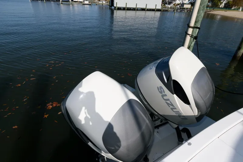 Slide: The Image of Twin Suzuki 350 engines on a 2005 Stamas 320 Express boat, docked by the water. - 10
