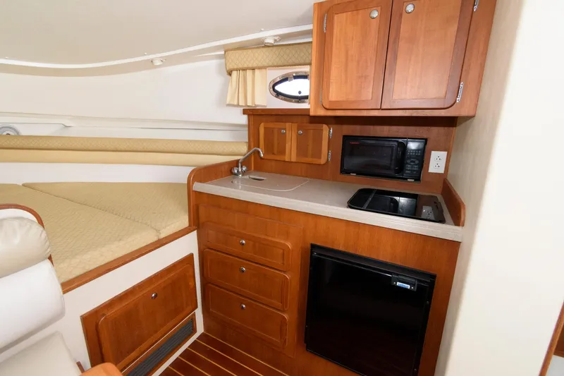 Slide: The Image of Interior of 2005 Stamas 320 Express with kitchenette, featuring wood cabinets, sink, and appliances. - 16