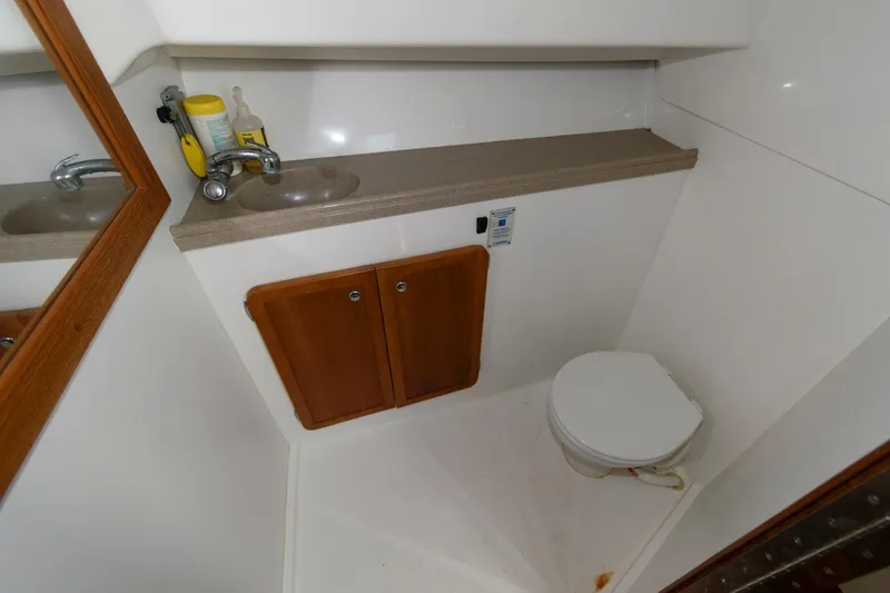 Slide: The Image of Compact bathroom in 2005 Stamas 320 Express boat, featuring sink, mirror, and toilet. - 20