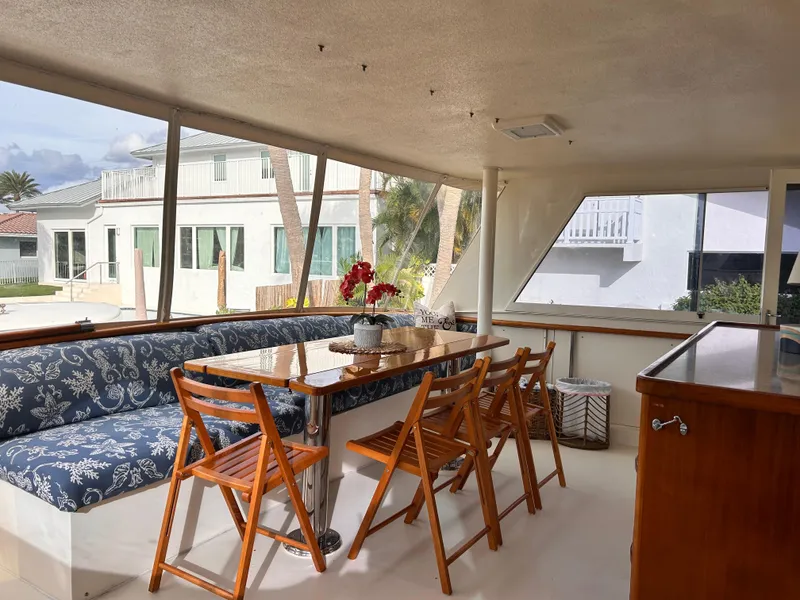 Slide: The Image of Interior of 1989 Hatteras 67 Cockpit Motor Yacht with dining area and wooden chairs. - 9