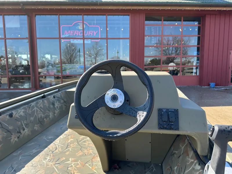 Slide: The Image of 2025 Tracker Grizzly 1648 SC boat steering wheel, parked outside Mercury dealership. - 3