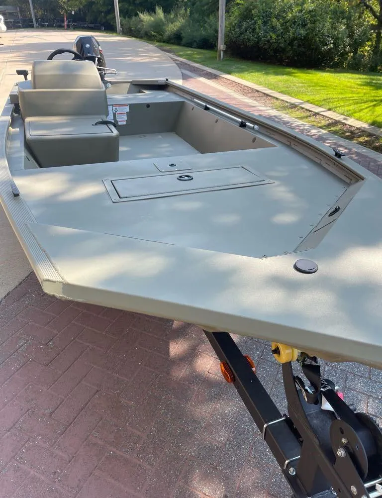 Slide: The Image of 2025 Tracker Grizzly 1648 SC boat on trailer, parked on a sunny street. - 2