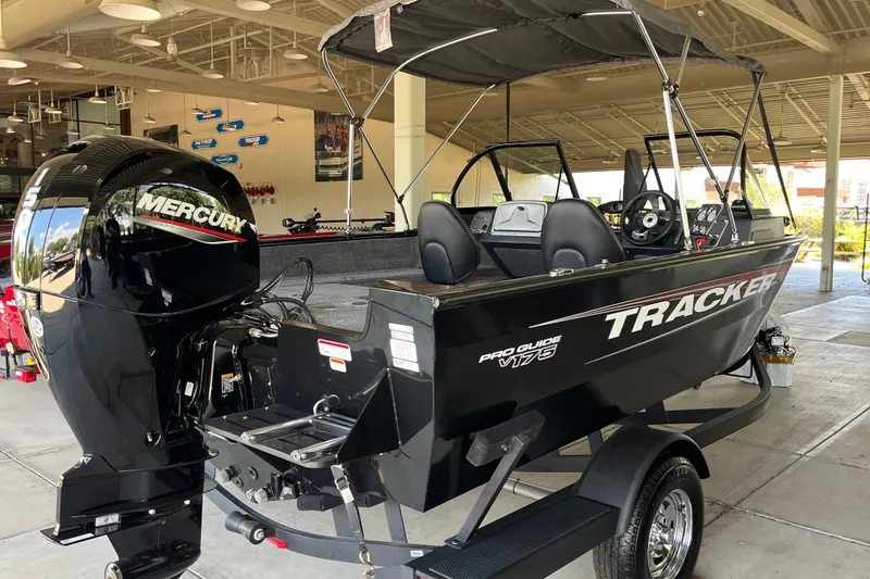 Slide: The Image of 2025 Tracker Pro Guide V-175 Combo boat with Mercury engine in showroom. - 2