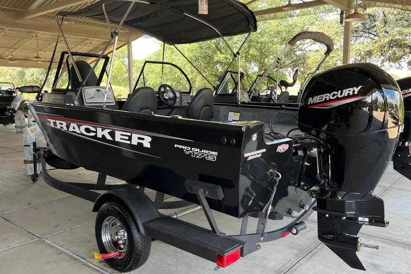 Slide: The Image of 2025 Tracker Pro Guide V-175 Combo boat with Mercury engine, parked under a canopy. - 3