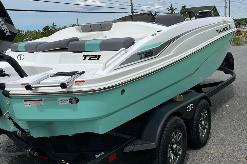 Slide: The Image of 2025 Tahoe T21 boat on trailer, mint green and white design, parked outdoors. - 7