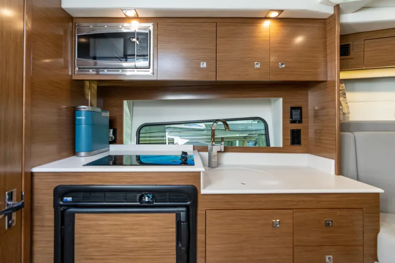 Slide: The Image of 2017 Cruisers Yachts 390 Express Coupe kitchen with wood cabinets, microwave, and sink. - 36