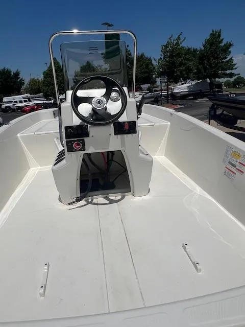 Slide: The Image of 2025 Mako Pro Skiff 17 CC boat interior with steering console, parked outdoors. - 4