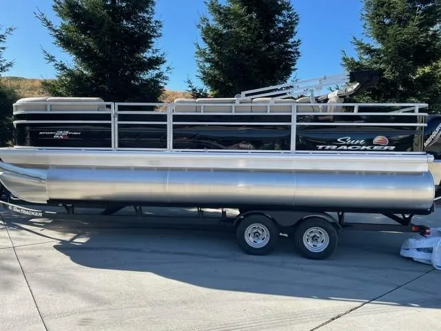 The Image of 2025 Sun Tracker SportFish 22 XP3 pontoon boat on trailer, parked outdoors. - 0