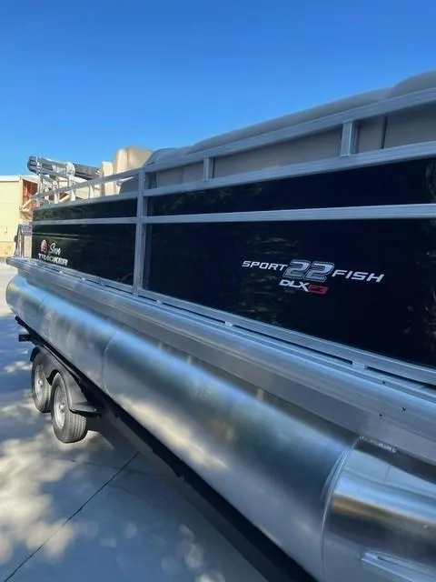 Slide: The Image of 2025 Sun Tracker SportFish 22 XP3 pontoon boat, sleek design, parked outdoors. - 3