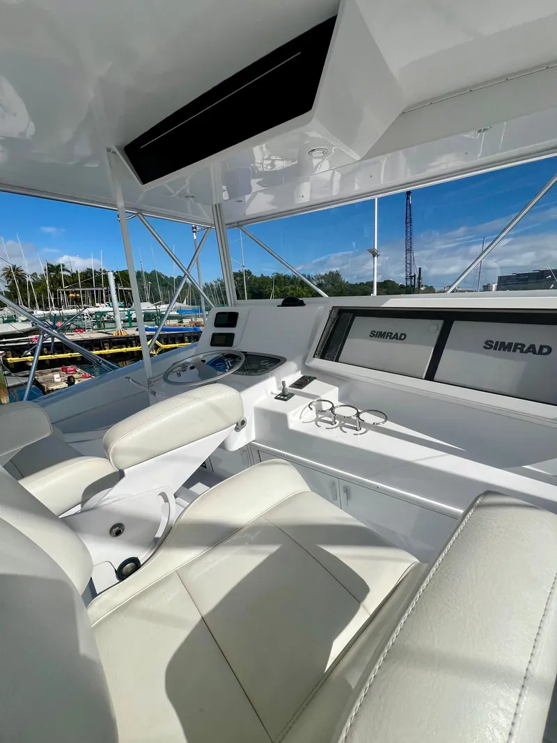 Slide: The Image of 1999 Viking Conv Sport Fisher cockpit with Simrad navigation, white leather seats, and marina view. - 40