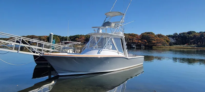 Slide: The Image of 2017 L&H 33 boat docked on calm water under clear blue sky. - 2
