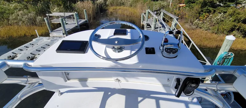 Slide: The Image of 2017 L&H 33 boat helm with steering wheel and controls, docked near marshland. - 28