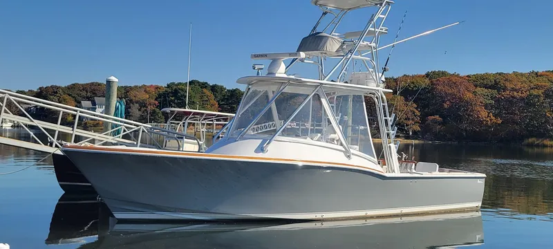 Slide: The Image of 2017 L&H 33 boat docked on calm water, clear sky background. - 33