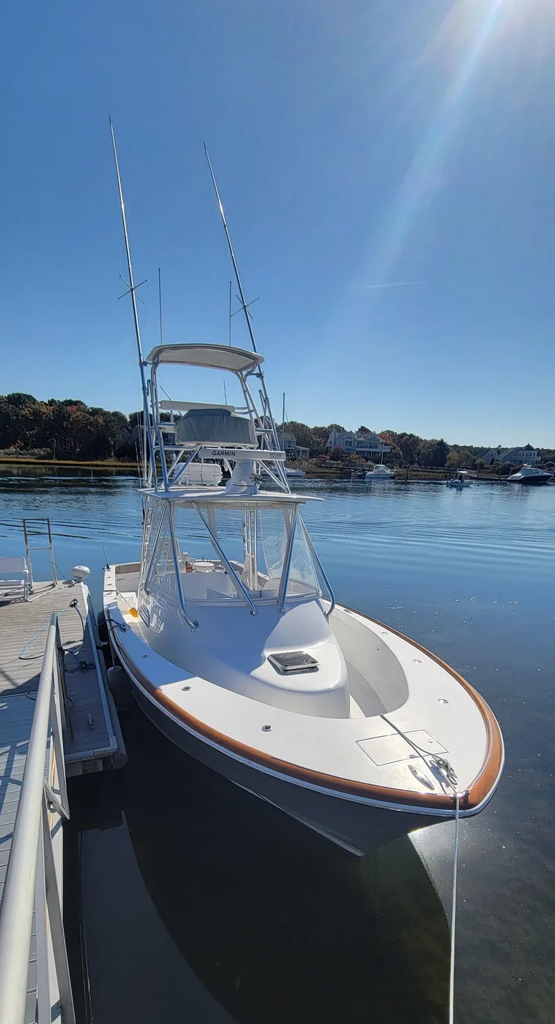 Slide: The Image of 2017 L&H 33 boat docked on calm water under clear blue sky. - 34