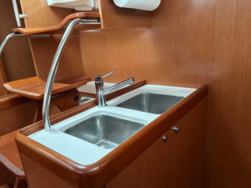 Slide: The Image of Beneteau Oceanis 46 (2008) kitchen sink area with dual basins and wooden cabinetry. - 44