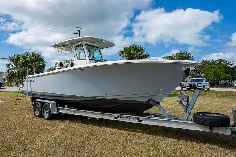 The Image of 2022 Sailfish 272CC boat on trailer, parked on grass under cloudy sky. - 1