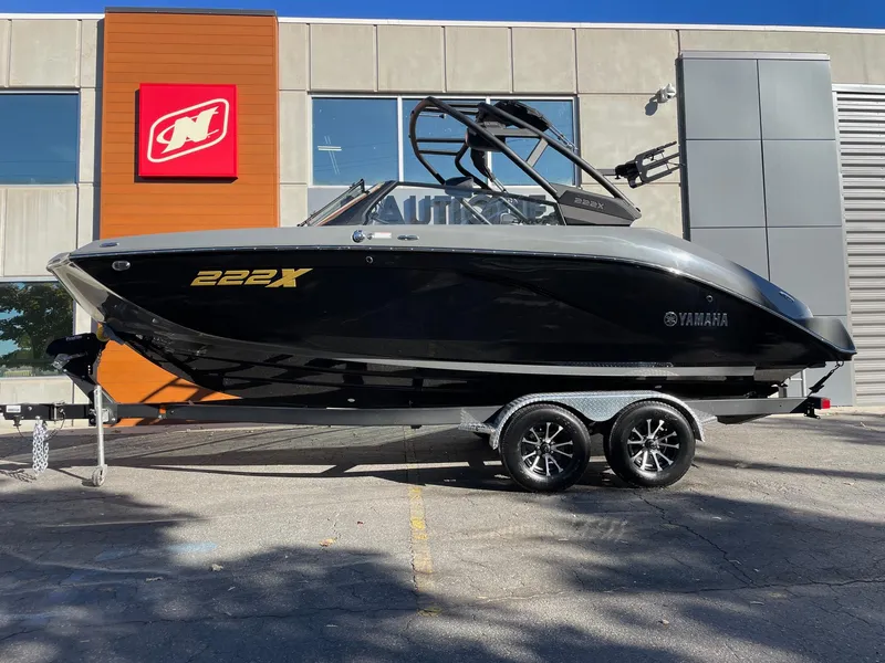 The Image of 2025 Yamaha Boats 222XD, sleek black design, on trailer outside dealership. - 1