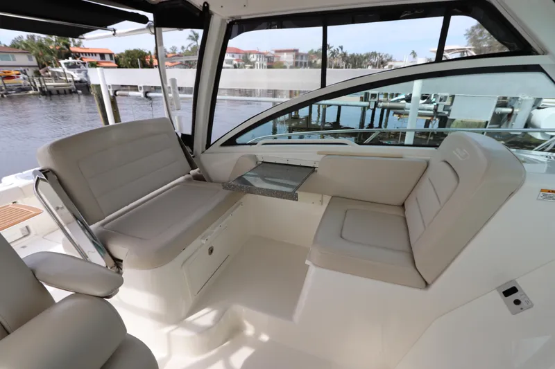 Slide: The Image of 2019 Boston Whaler 315 Conquest interior with beige seating and table, dockside view. - 23