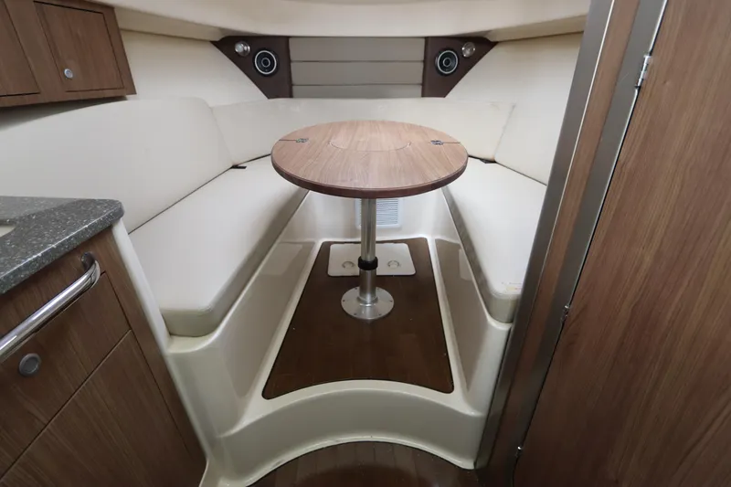 Slide: The Image of 2019 Boston Whaler 315 Conquest cabin interior with wood accents and round table. - 36