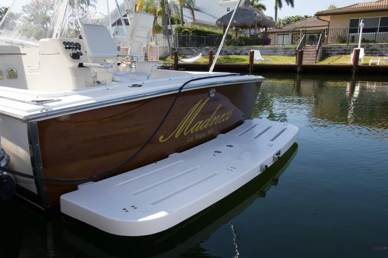 Slide: The Image of 1997 Lazzara Aura Tournament boat docked, featuring a wooden transom and white swim platform. - 10