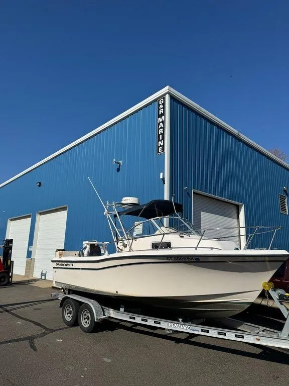 Slide: The Image of Grady-White 202 Adventure 2000 boat on trailer, parked outside blue marine warehouse. - 4