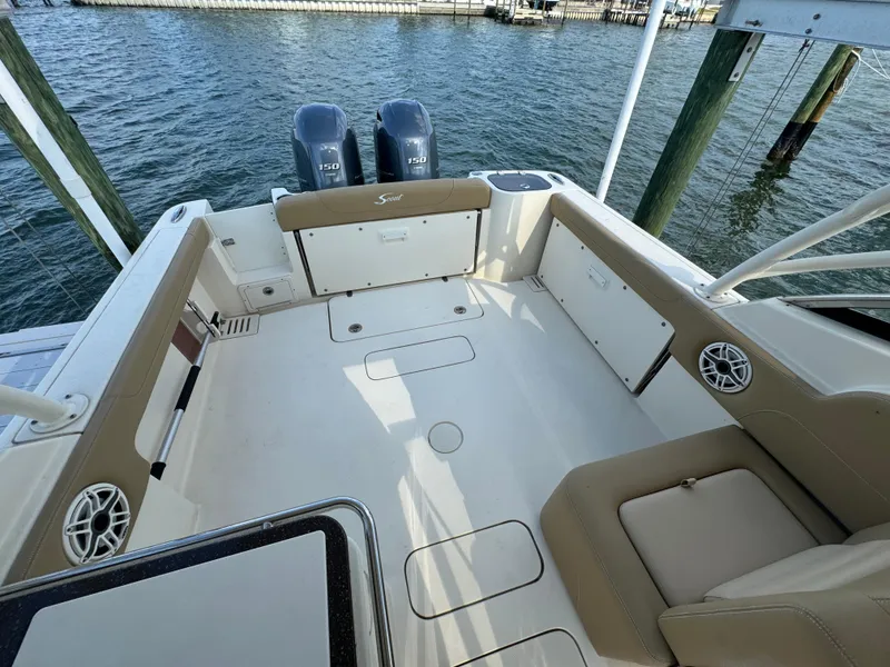 Slide: The Image of 2021 Scout 255 Dorado boat interior with helm and seating, docked by the water. - 21