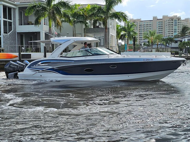 The Image of 2023 Formula 350 Crossover Bowrider cruising near waterfront homes and palm trees. - 1