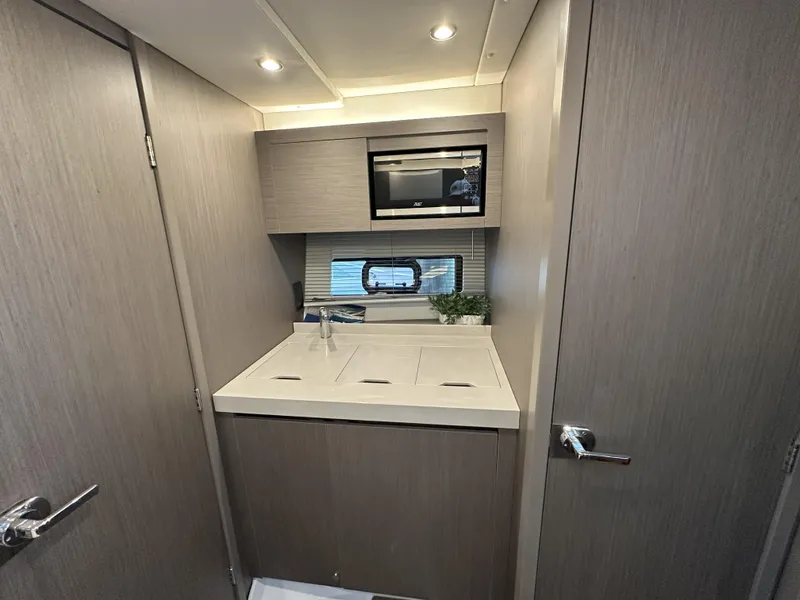 Slide: The Image of Modern kitchenette in 2025 Beneteau Gran Turismo 36 yacht, featuring sleek cabinetry and built-in microwave. - 18