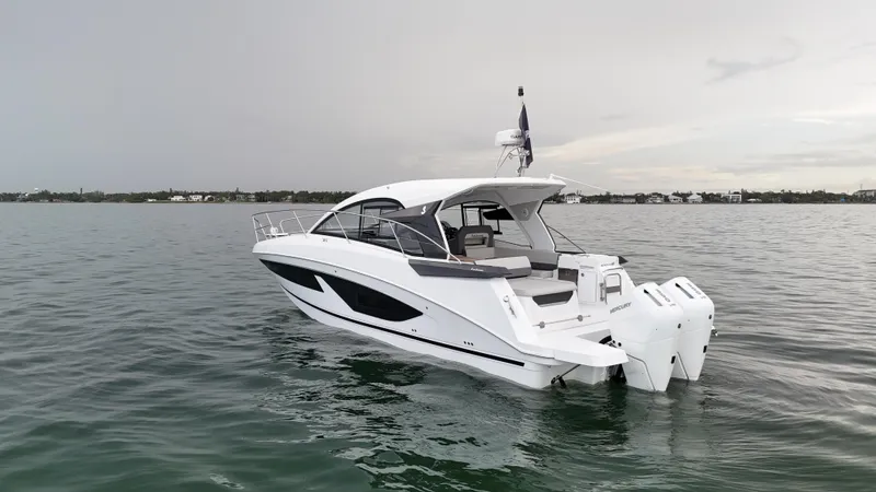 Slide: The Image of 2025 Beneteau Gran Turismo 36 yacht on calm water, showcasing sleek design and twin outboard engines. - 5