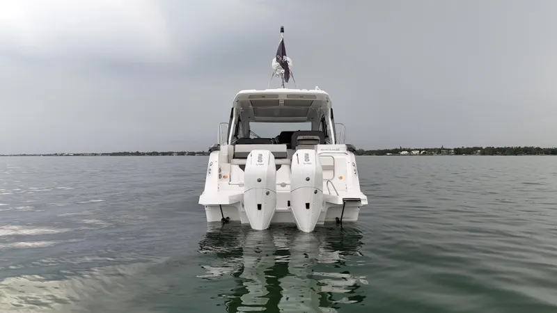 Slide: The Image of 2025 Beneteau Gran Turismo 36 yacht on calm water, rear view with dual engines. - 6