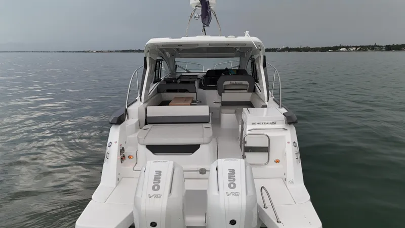 Slide: The Image of 2025 Beneteau Gran Turismo 36 yacht on calm water, rear view with twin Mercury engines. - 7