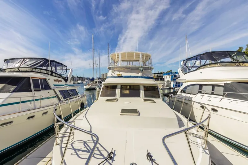 Slide: The Image of 1983 Uniflite 42 Aft Cabin yacht docked among other boats under a clear blue sky. - 13