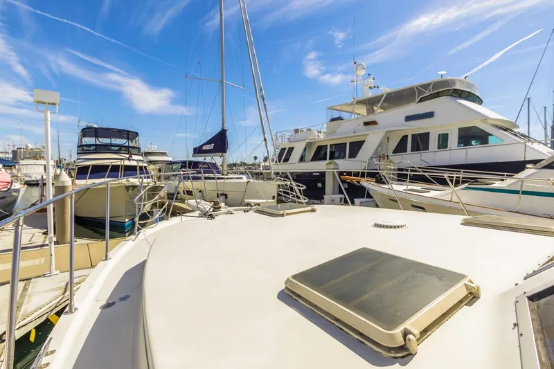 Slide: The Image of 1983 Uniflite 42 Aft Cabin yacht docked in a marina under a clear blue sky. - 16