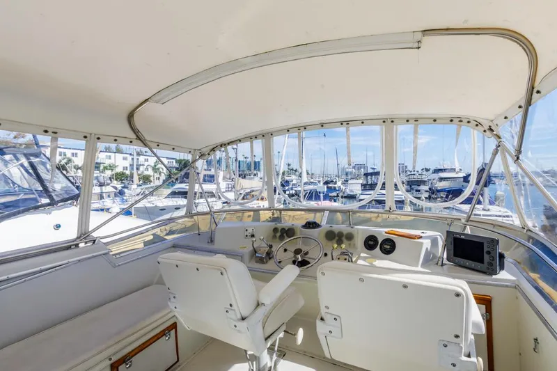 Slide: The Image of Interior view of 1983 Uniflite 42 Aft Cabin yacht helm with marina background. - 17