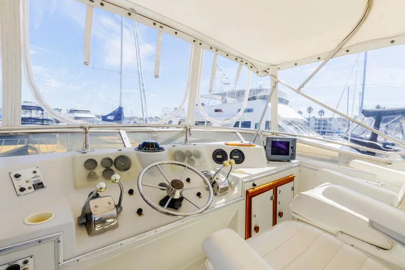 Slide: The Image of 1983 Uniflite 42 Aft Cabin yacht helm with marina view, featuring classic controls and seating. - 20