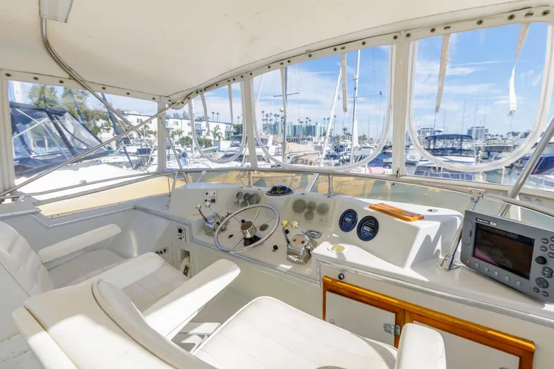 Slide: The Image of 1983 Uniflite 42 Aft Cabin yacht helm with marina view, featuring navigation instruments. - 21
