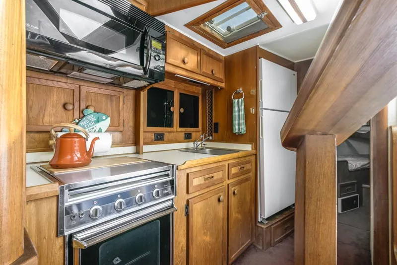 Slide: The Image of 1983 Uniflite 42 Aft Cabin kitchen with wood cabinetry and modern appliances. - 30