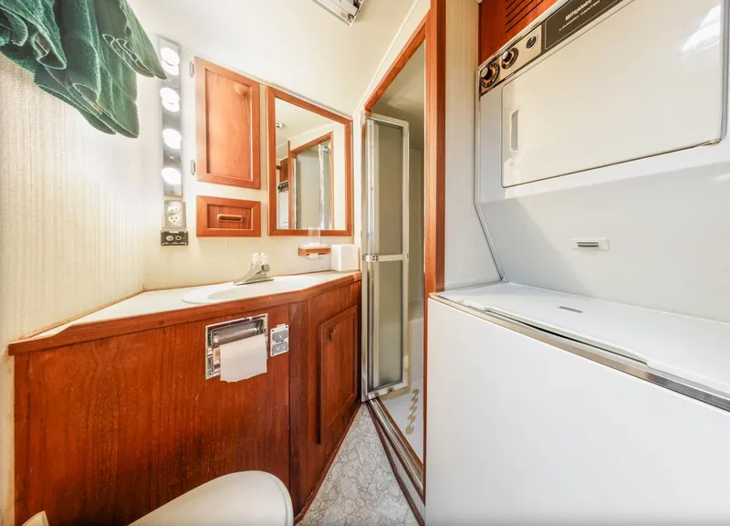 Slide: The Image of 1983 Uniflite 42 Aft Cabin bathroom with wood cabinetry and washer-dryer unit. - 33