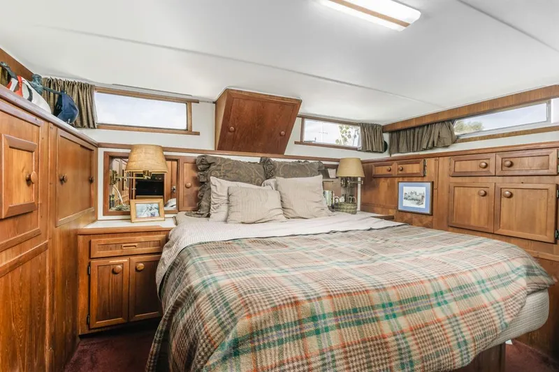 Slide: The Image of 1983 Uniflite 42 Aft Cabin bedroom with wood cabinetry and plaid bedding. - 39