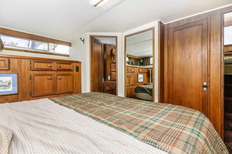 Slide: The Image of 1983 Uniflite 42 Aft Cabin interior with wood cabinetry and plaid bedding. - 41