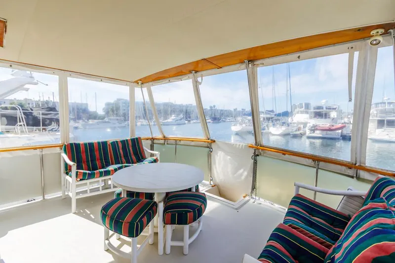 Slide: The Image of 1983 Uniflite 42 Aft Cabin yacht interior with striped seating and marina view. - 8