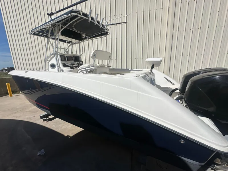 Slide: The Image of 2003 Boston Whaler 270 Outrage boat with dual engines, docked near a warehouse. - 2