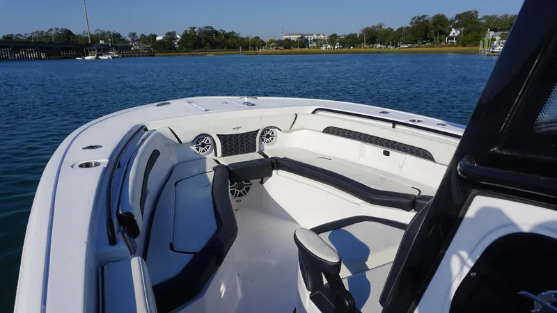 Slide: The Image of 2024 Tidewater 256 CC Adventure boat interior with seating and speakers on a calm lake. - 11