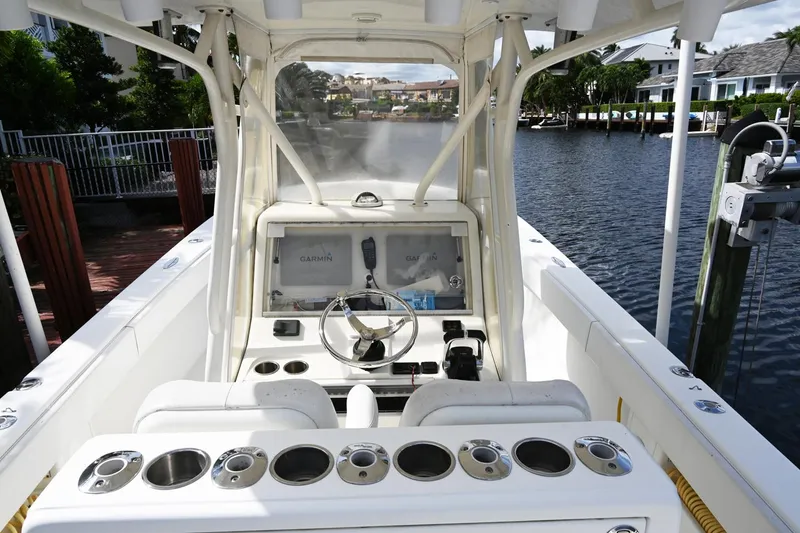 Slide: The Image of 2016 SeaVee 340Z boat cockpit with steering wheel, control panel, and cup holders on a calm waterway. - 17