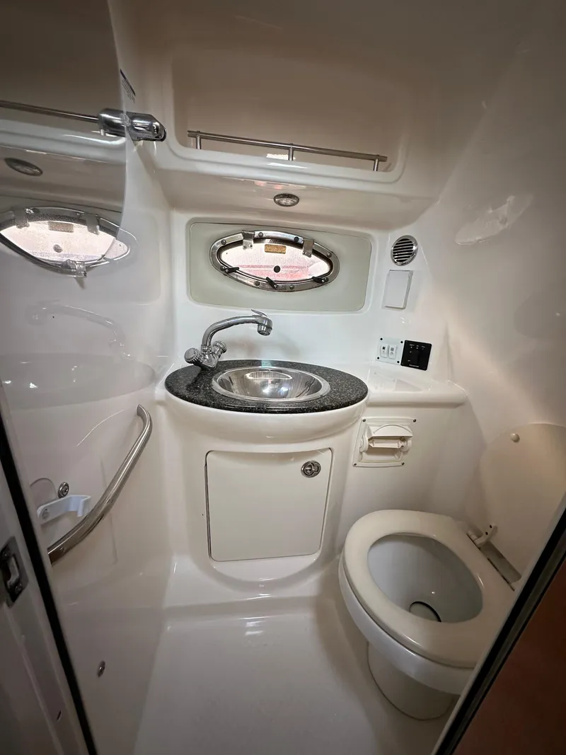 Slide: The Image of 2007 Chaparral Signature 270 boat bathroom with sink, toilet, and porthole window. - 11