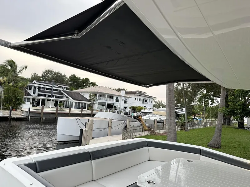 Slide: The Image of Galeon 650 Sky 2019 yacht with shaded seating area, docked near waterfront homes. - 32