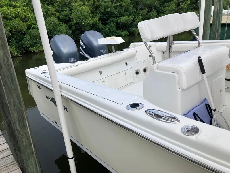 Slide: The Image of 2005 Sailfish 266 CC boat with dual outboard motors docked by lush greenery. - 11