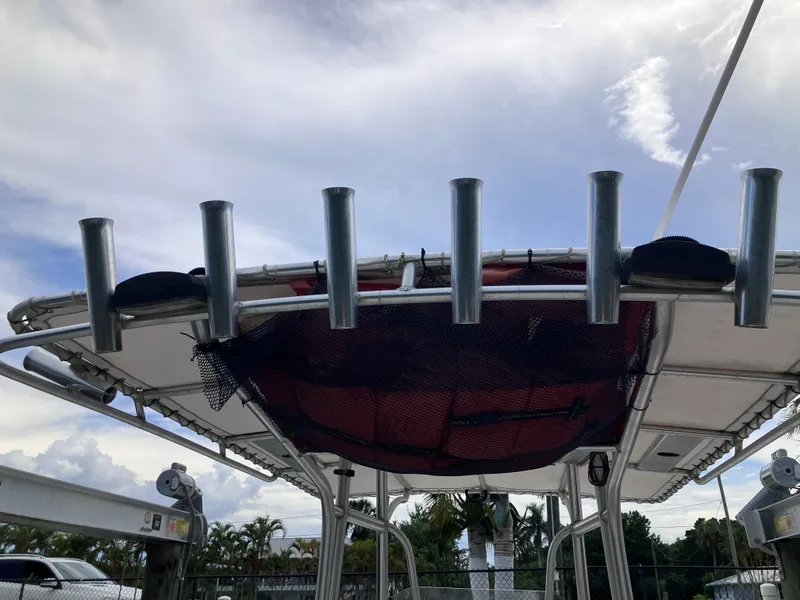 Slide: The Image of 2005 Sailfish 266 CC boat with rod holders and canopy under a cloudy sky. - 20
